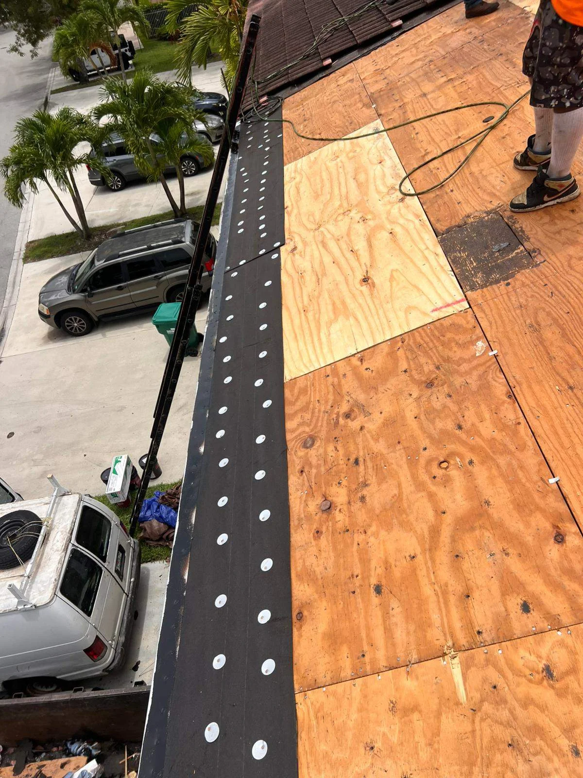 Roof repair in progress with plywood patching and protective coverings installed.