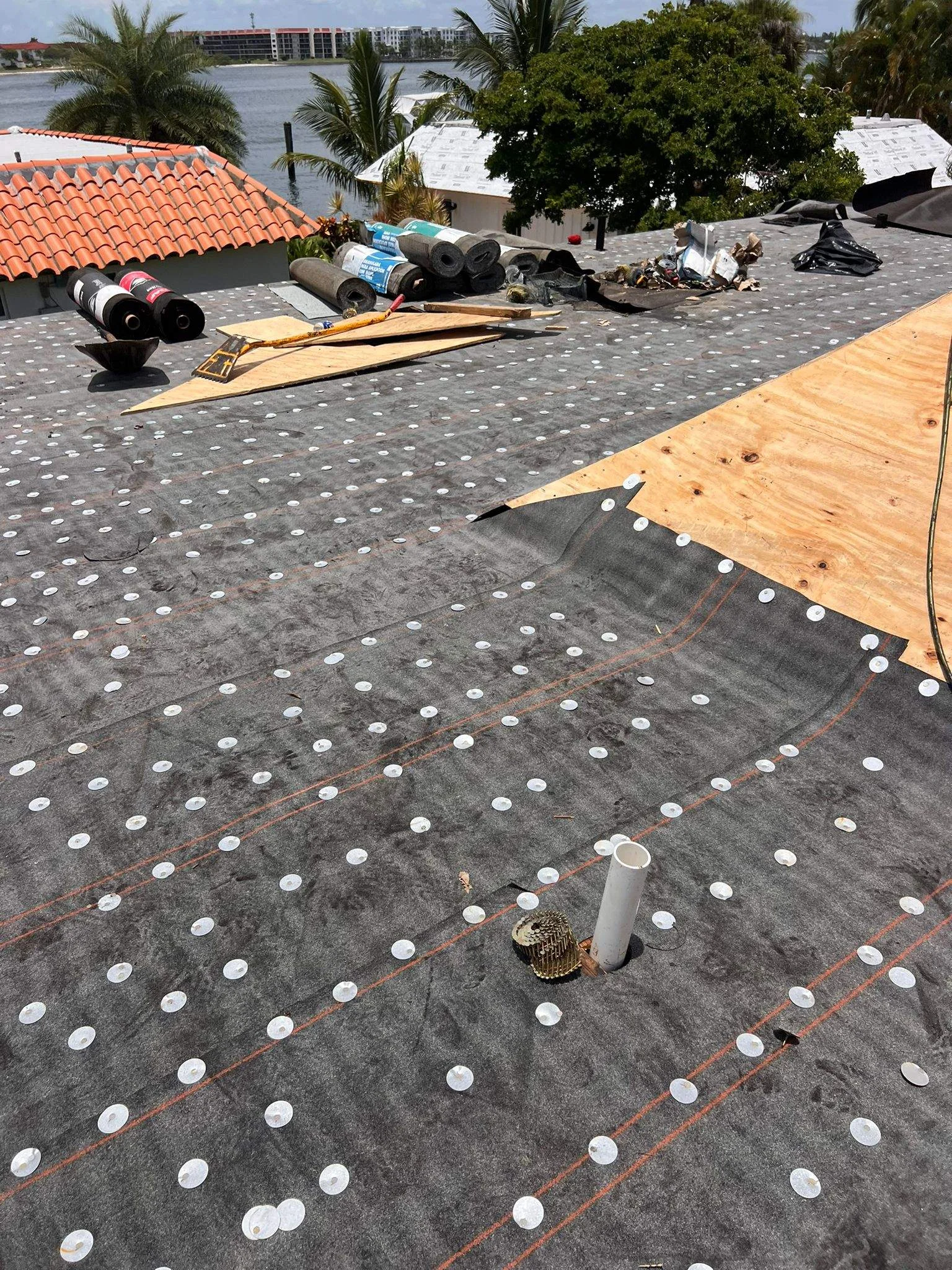 Roof membrane installation in progress with ventilation ducts and protective caps on waterproof substrate.