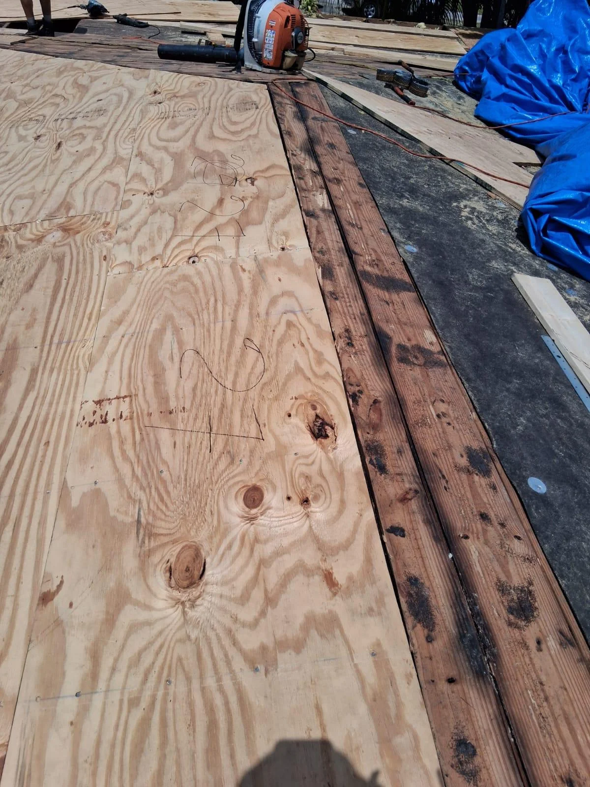 Roofing installation in progress with shingles, underlayment, and tools on residential roof.
