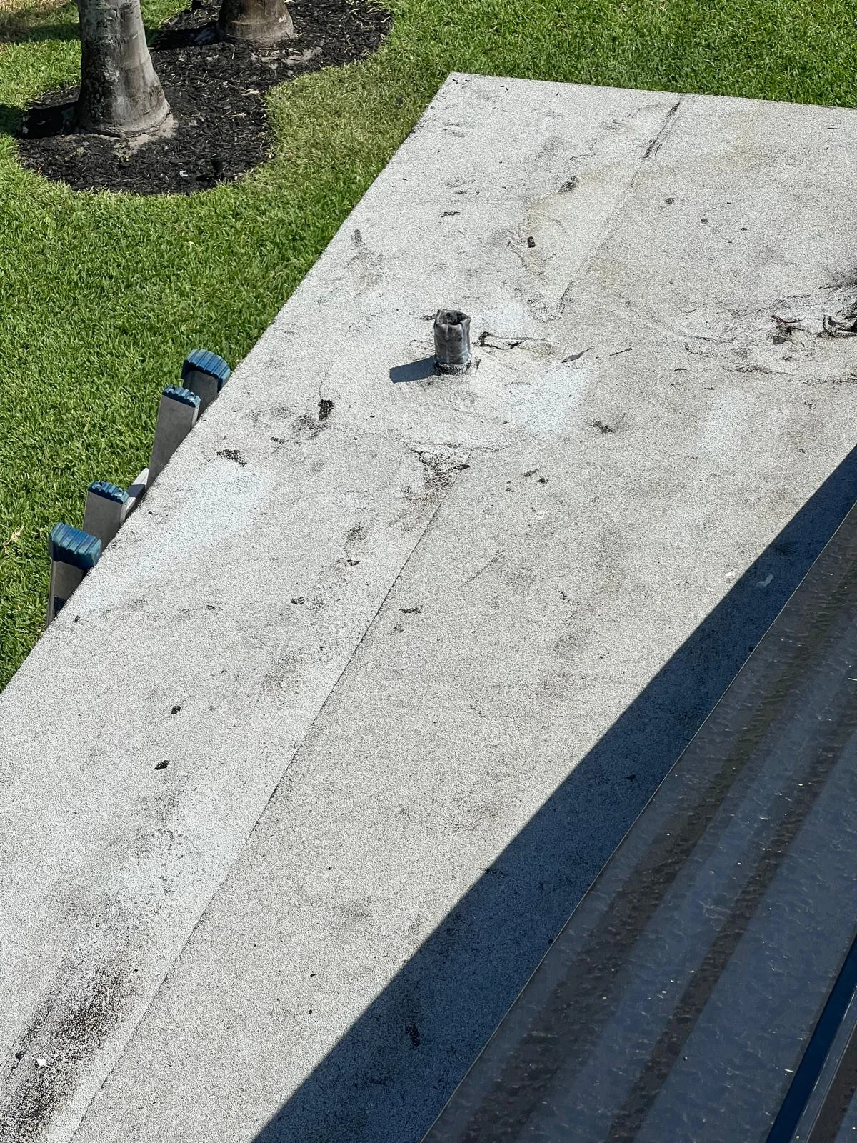 Asphalt roof with visible wear, debris, and gutter system in daylight.